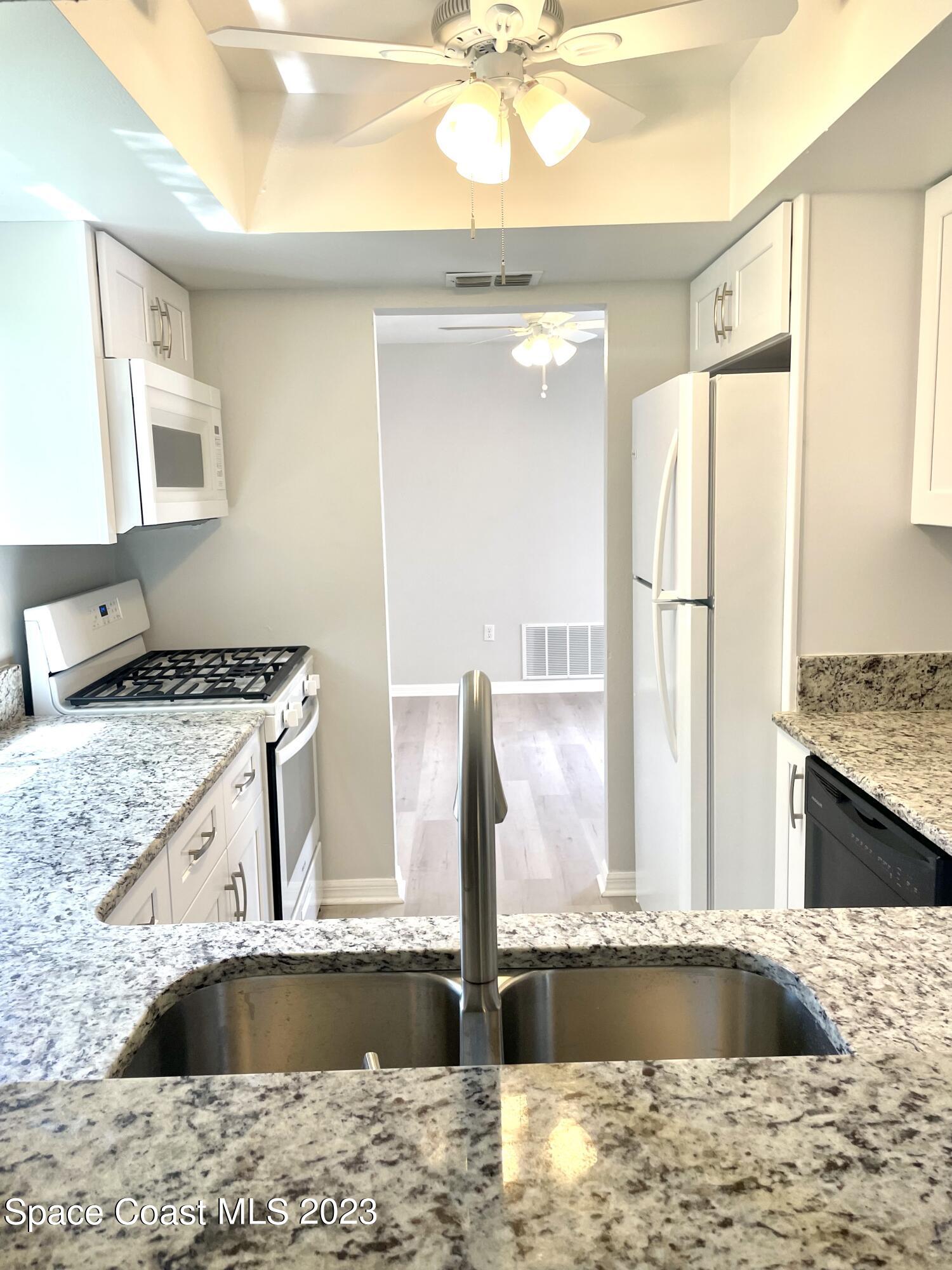 179 Shell Place, Unit 36 Rockledge, FL 32955 - Photo 4 of 20 a kitchen with a sink granite counter tops and a wooden cabinets