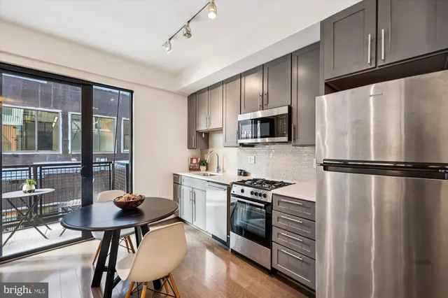 a kitchen with stainless steel appliances a stove a refrigerator a sink dishwasher with a dining table and chairs