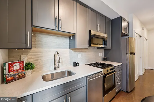 a kitchen with stainless steel appliances a sink a stove a microwave a refrigerator and cabinets