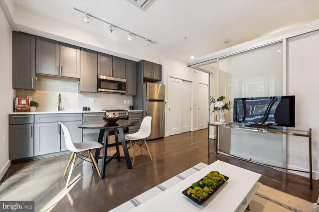 a kitchen with stainless steel appliances a microwave a stove a sink dishwasher a refrigerator and cabinets with wooden floor