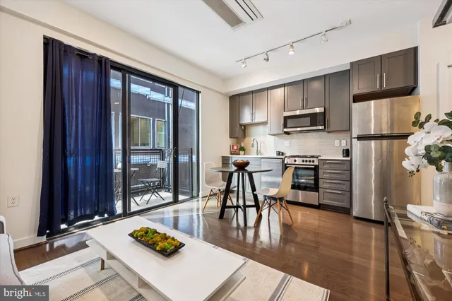 a kitchen with stainless steel appliances granite countertop a refrigerator a stove top oven a sink dishwasher and white cabinets with wooden floor