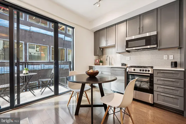 a kitchen with stainless steel appliances kitchen island granite countertop a stove top oven a sink dishwasher a dining table and chairs with wooden floor