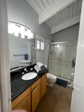a bathroom with a granite countertop sink a toilet a mirror and shower