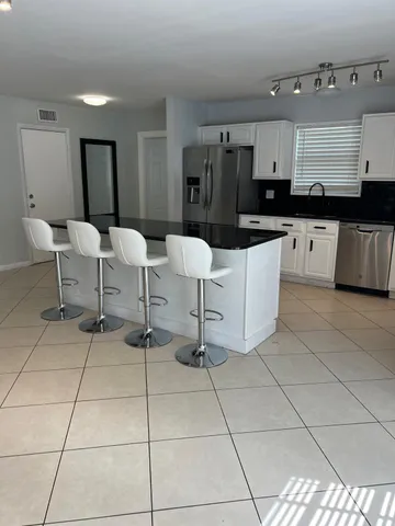 a kitchen with stainless steel appliances kitchen island granite countertop a refrigerator a stove a microwave and a dining table with wooden floor