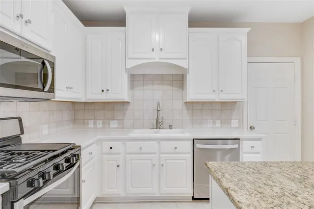 a kitchen with white cabinets and sink