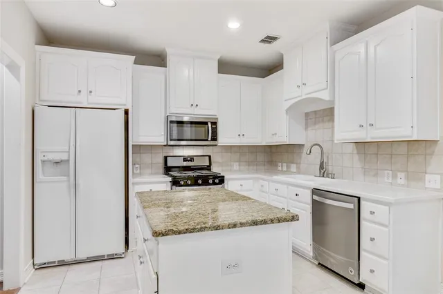 a kitchen with white cabinets and stainless steel appliances