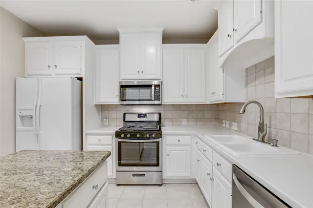 a kitchen with white cabinets and appliances