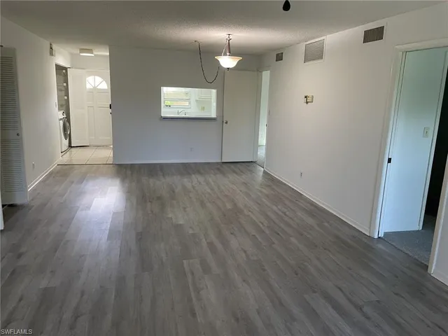 a view of an empty room with wooden floor and a mirror