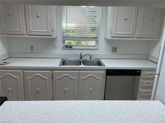 a kitchen with white cabinets a sink and a window
