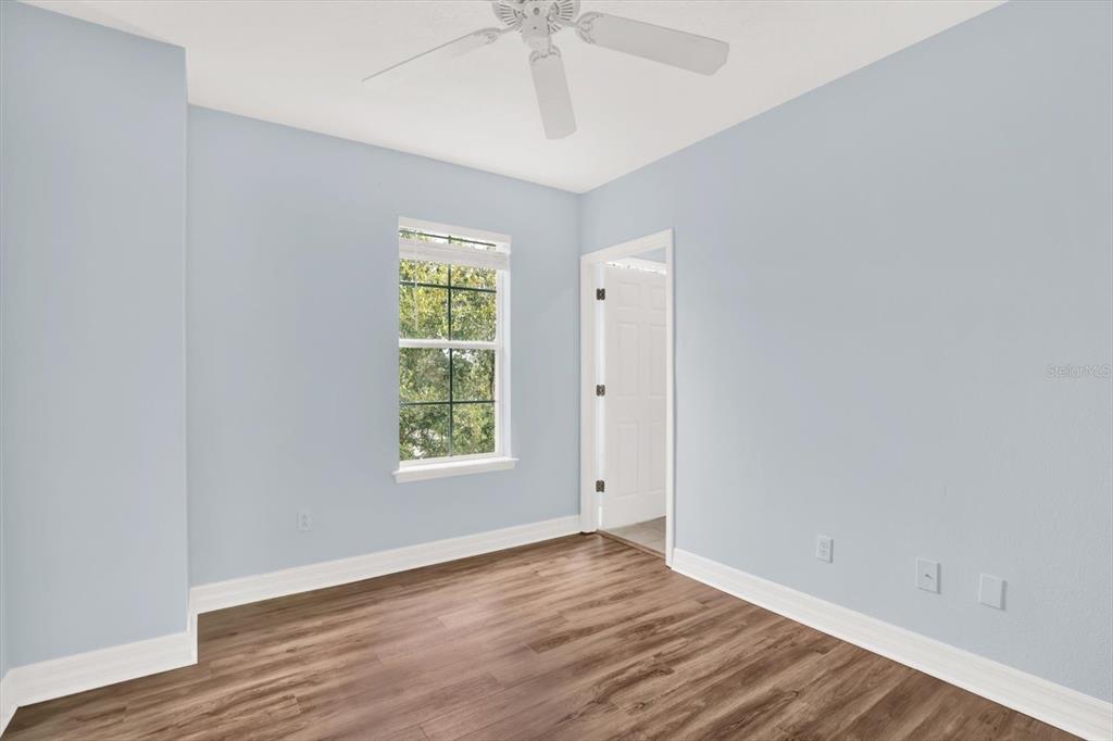 4529 Bay Spring Court Tampa, FL 33611 - Photo 29 of 66 an empty room with wooden floor chandelier fan and windows