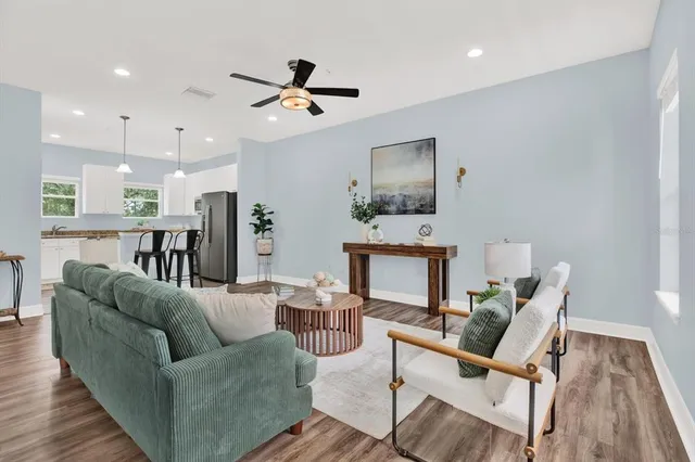 a living room with furniture kitchen view and a wooden floor