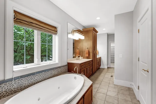 a bathroom with a tub a sink and a large mirror