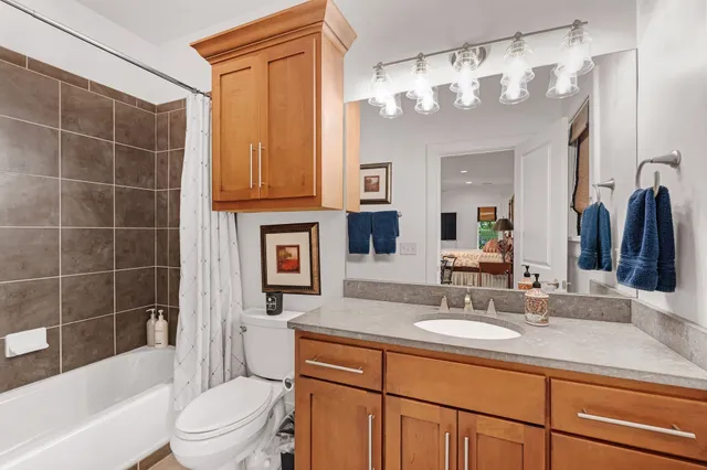 a bathroom with a granite countertop sink a toilet a mirror a vanity a bathtub and shower