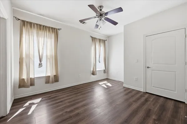 a view of an empty room with a window and wooden floor