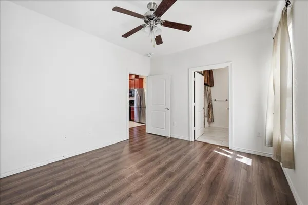 an empty room with wooden floor ceiling fan and windows