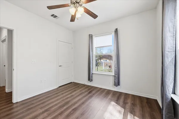 a view of empty room with wooden floor and fan