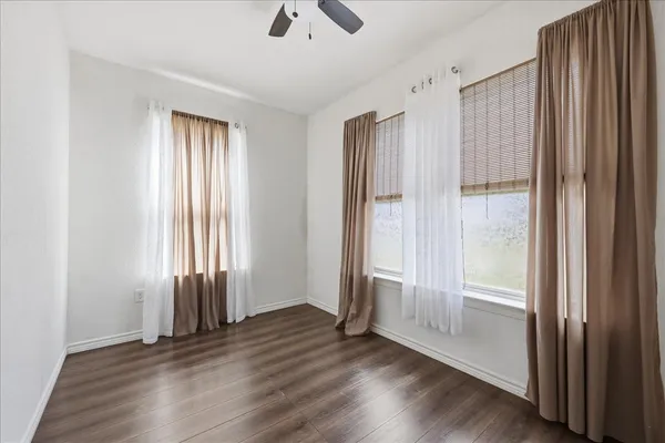 an empty room with wooden floor door and windows