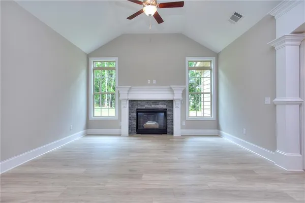 a view of an empty room with wooden floor fireplace and a window