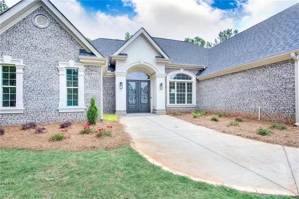 an empty room with wooden floor chandelier and windows