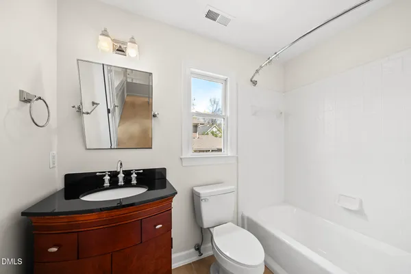a bathroom with a granite countertop sink toilet a mirror and shower