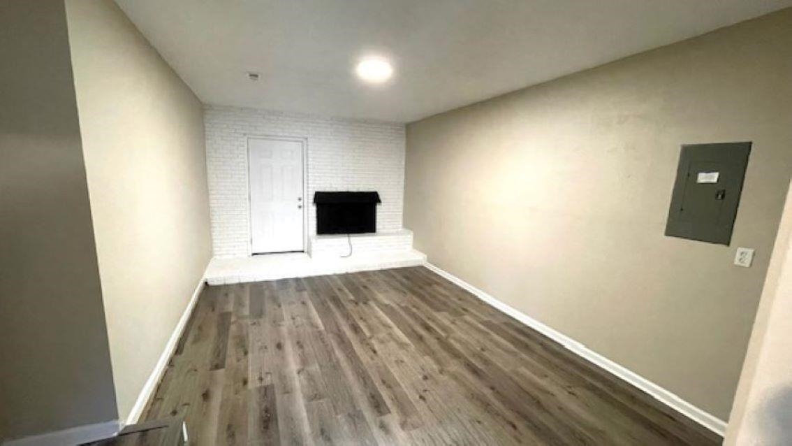 4704 Bill Knight Road Millington, TN 38053 - Photo 13 of 17 Unfurnished living room with electric panel, a large fireplace, dark wood-type flooring, and brick wall