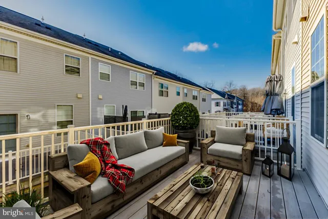a roof deck with couches and potted plants with wooden floor