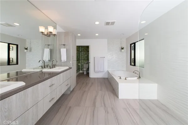 a spacious bathroom with a double vanity sink a mirror and a bathtub