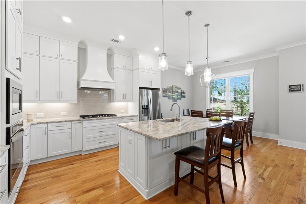 206 Trecastle Square Canton, GA 30114 - Photo 6 of 49 a kitchen with stainless steel appliances granite countertop a stove a sink a oven a dining table and chairs with wooden floor