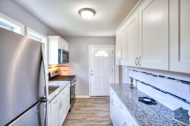 a kitchen with granite countertop a refrigerator a sink and wooden cabinets