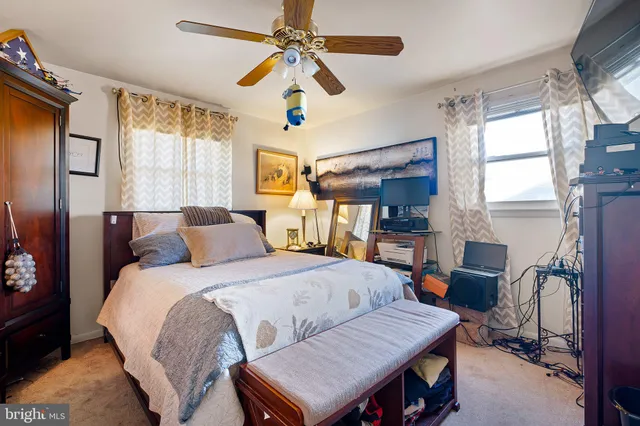 a bedroom with a bed a desk and chair with the large windows