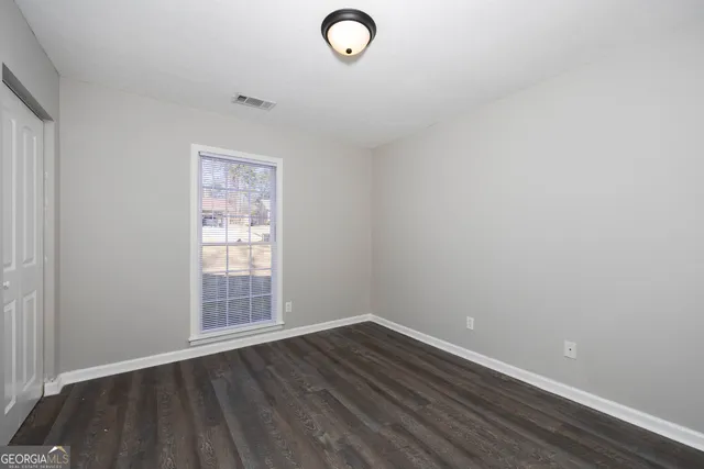 an empty room with wooden floor and windows