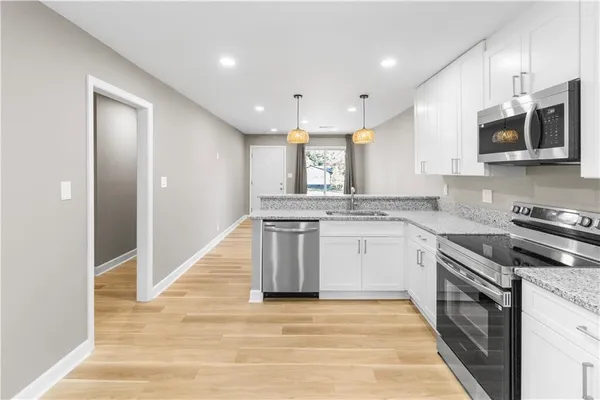 a kitchen with stainless steel appliances granite countertop a stove top oven a sink and a microwave