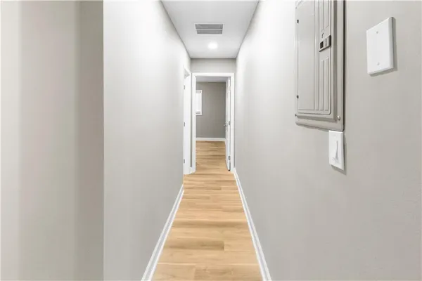 a view of a hallway with wooden floor and a bathroom