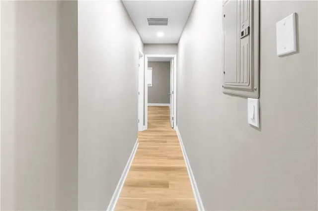 a view of a hallway with wooden floor and a bathroom