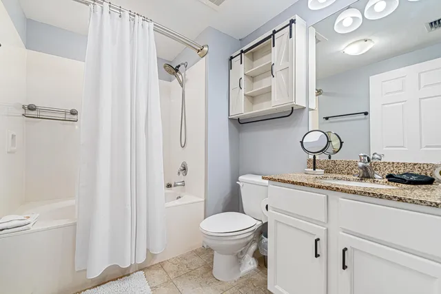 a bathroom with a granite countertop sink toilet a mirror and shower