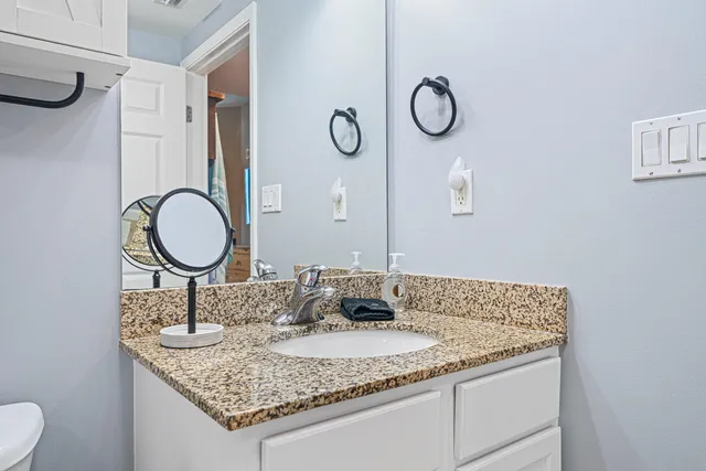 a bathroom with a granite countertop sink and a mirror