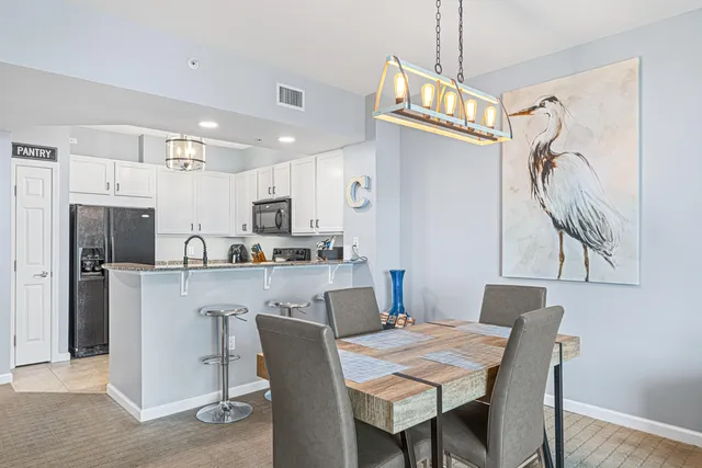 a kitchen with stainless steel appliances granite countertop a dining table chairs refrigerator and microwave