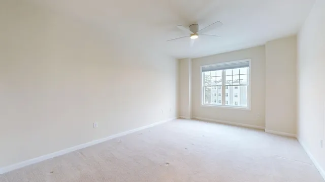 an empty room with a ceiling fan and window