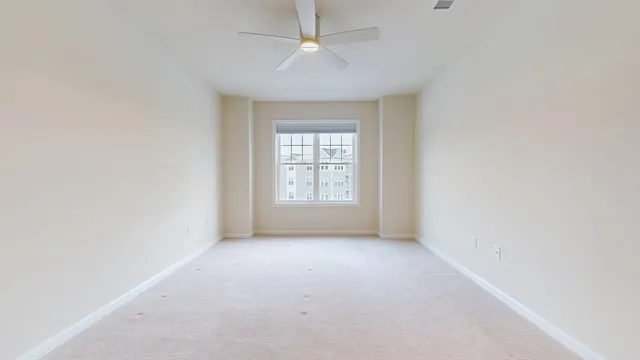 an empty room with a window and a ceiling fan