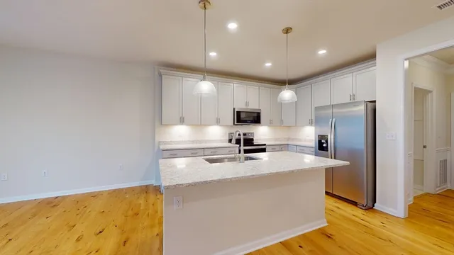 a kitchen with stainless steel appliances granite countertop a sink a stove a refrigerator a center island with cabinets and wooden floor