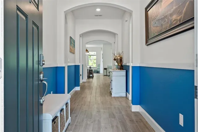 a kitchen with stainless steel appliances granite countertop a stove a sink a microwave a refrigerator and white cabinets with wooden floor