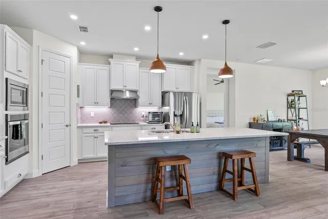 a kitchen with stainless steel appliances granite countertop a refrigerator a sink dishwasher a stove and a refrigerator with wooden floor