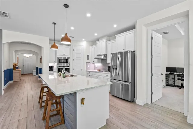 a living room with stainless steel appliances kitchen island granite countertop furniture a rug a fireplace and a kitchen view