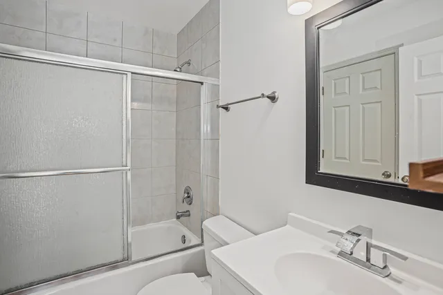 a bathroom with a granite countertop bathtub shower sink vanity and toilet