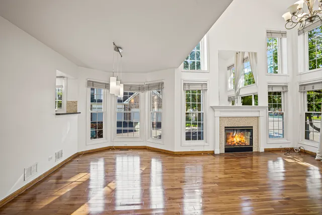 a view of an empty room with wooden floor and a fireplace