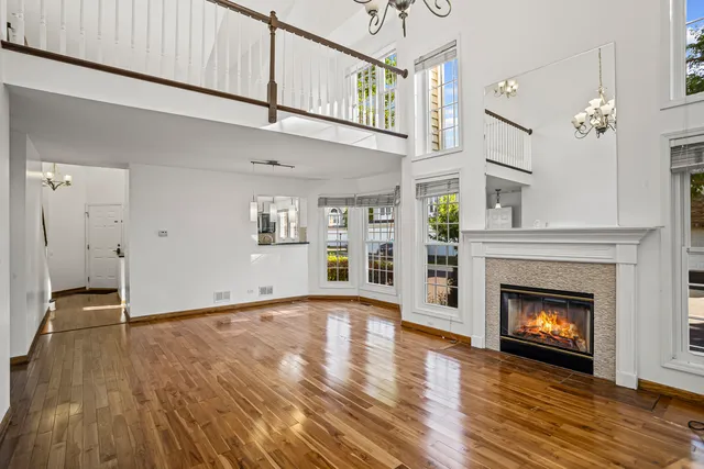 a view of an empty room with wooden floor and a fireplace