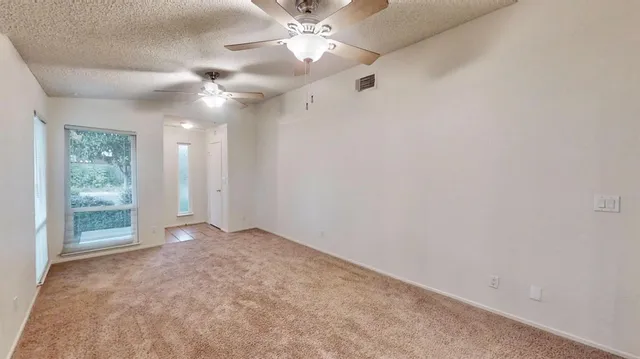 en empty room with windows and ceiling fan