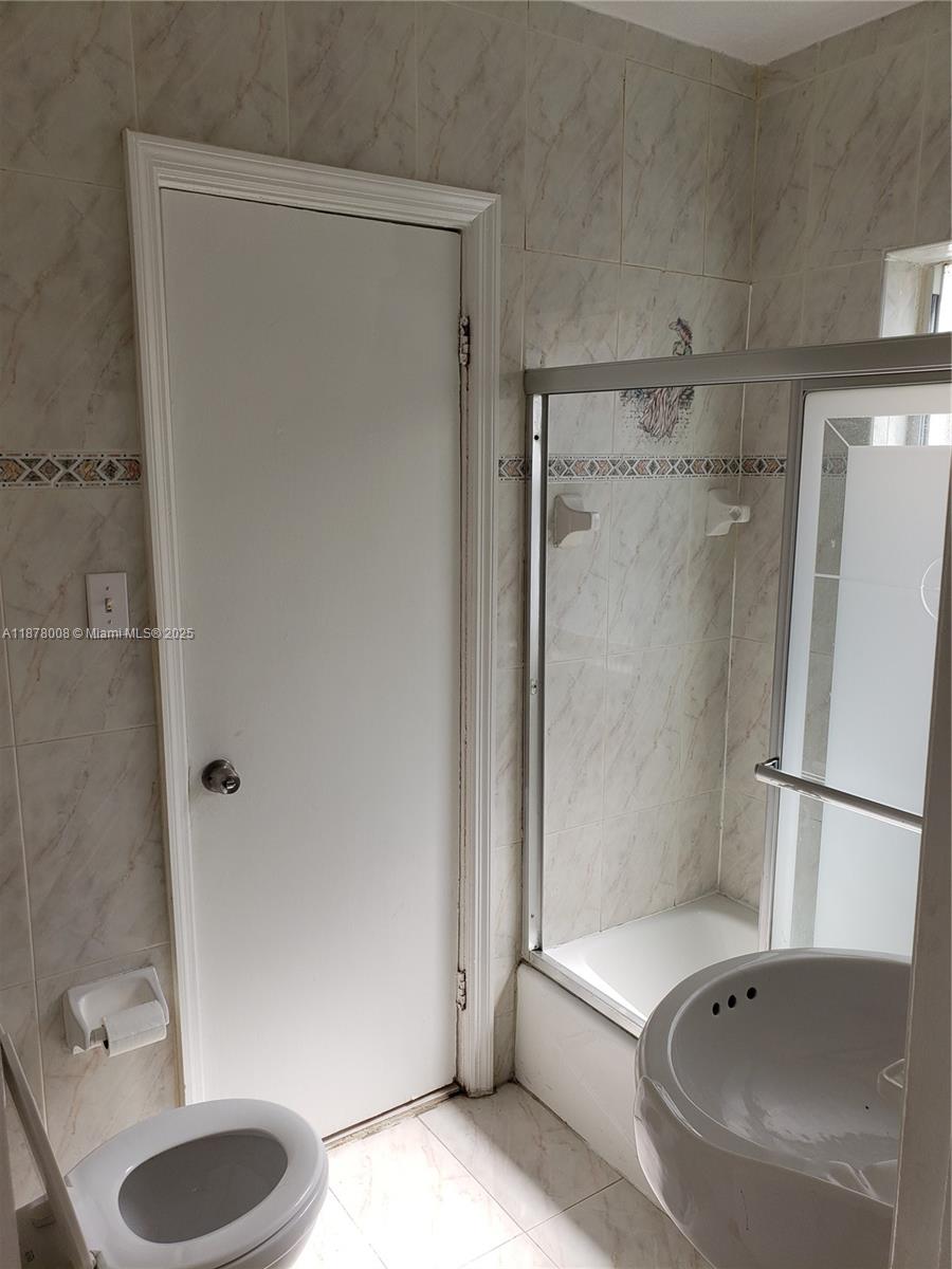 6912 Northeast 5th Avenue, Unit 2 Miami, FL 33138 - Photo 11 of 18 a bathroom with a granite countertop bathtub shower sink and toilet