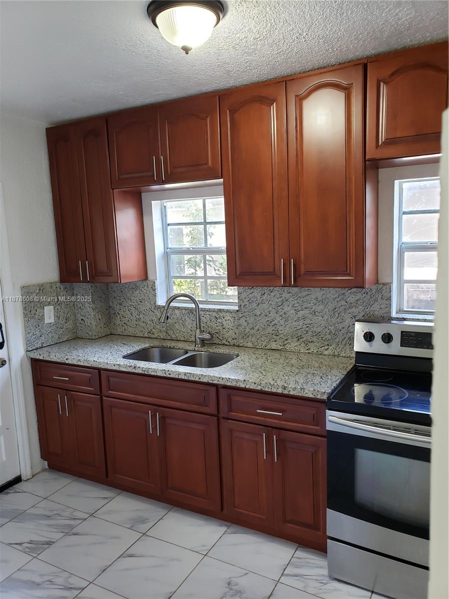 6912 Northeast 5th Avenue, Unit 2 Miami, FL 33138 - Photo 4 of 18 a kitchen with stainless steel appliances granite countertop wooden cabinets a stove and a sink