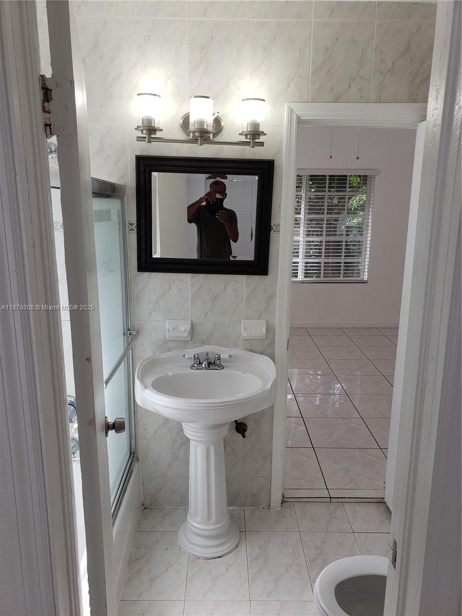 6912 Northeast 5th Avenue, Unit 2 Miami, FL 33138 - Photo 9 of 18 a bathroom with a sink a toilet and mirror